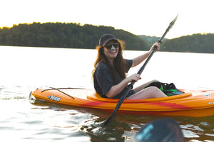 girl on kayak in the outdoors wearing colorful sunscreen on her nose 